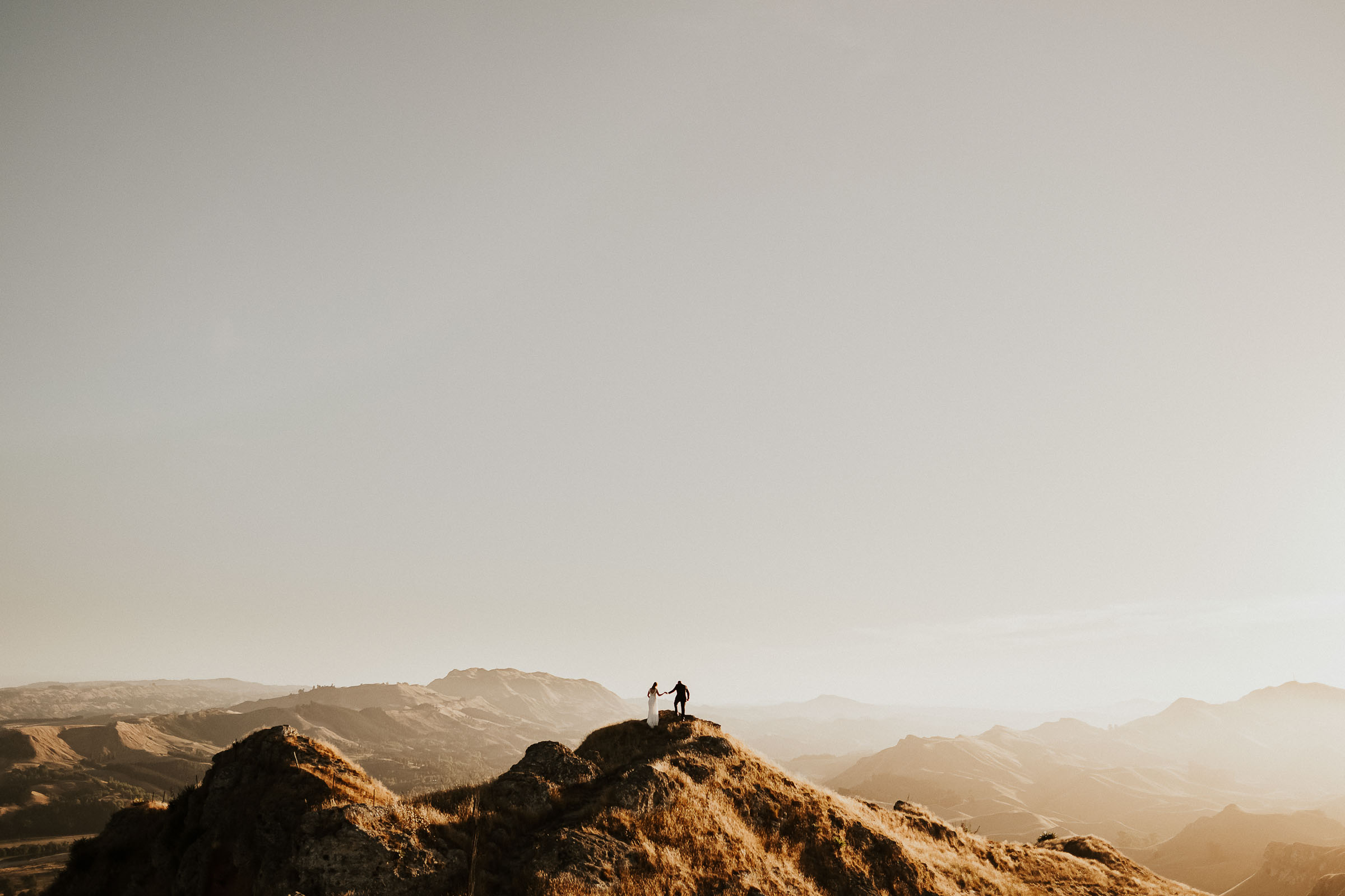 A wedding couple climb Te Mata peak at sunset, captured by Patina Photo.